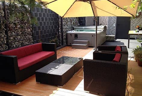 Terrasse mit Sitzmöbeln und Sonnenschirm neben dem Whirlpool