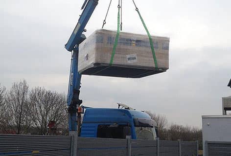 Ein Kran hebt den Whirlpool über den Sichtschutz des Gartens